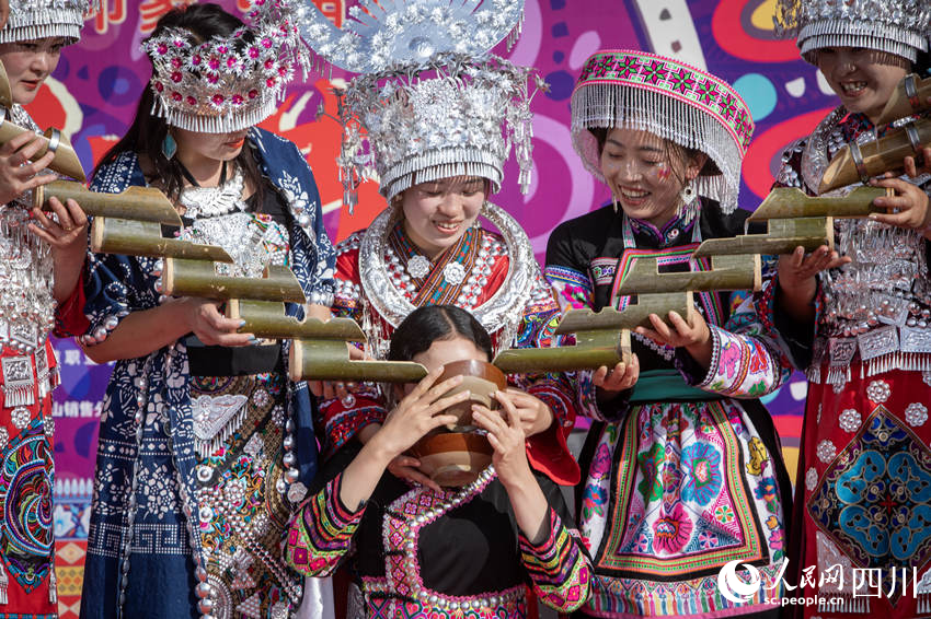 游客在体验苗族传统民俗。何为摄