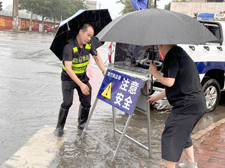 工作人员雨中放置警示牌。绵竹市融媒体中心供图