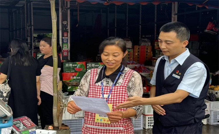 雙流航空港支行人員在成都農產品批發市場為商戶介紹聚合支付服務。建行四川省分行供圖