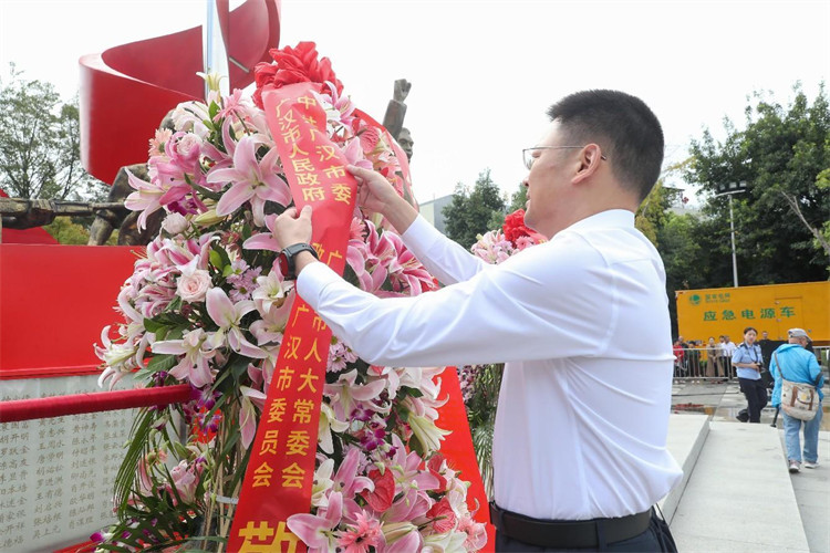 廣漢市市委書記王銳整理花籃緞帶。廣漢市融媒體中心供圖