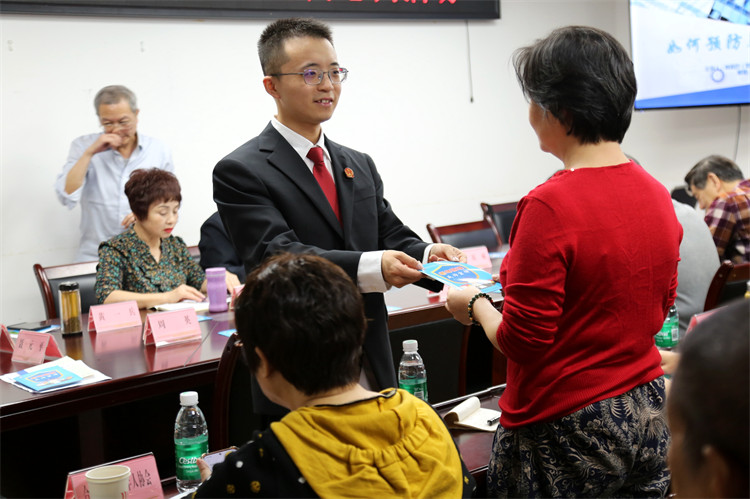 法院干警向老年朋友发防范放养老诈骗法治宣传资料。翠屏区人民法院供图