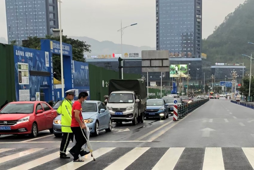 罗文搀扶行动不便的病人过马路。四川公安供图