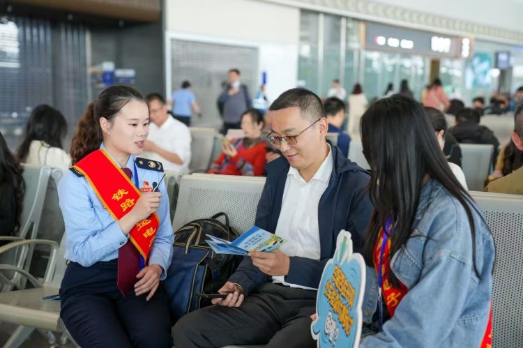 税务干部在火车站候车室向乘客宣传开具电子发票相关知识。成都市税务局供图