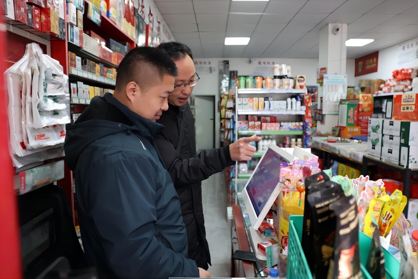 客户经理邹亦雷指导陈刚（左一）使用收银机。杨雪艺供图