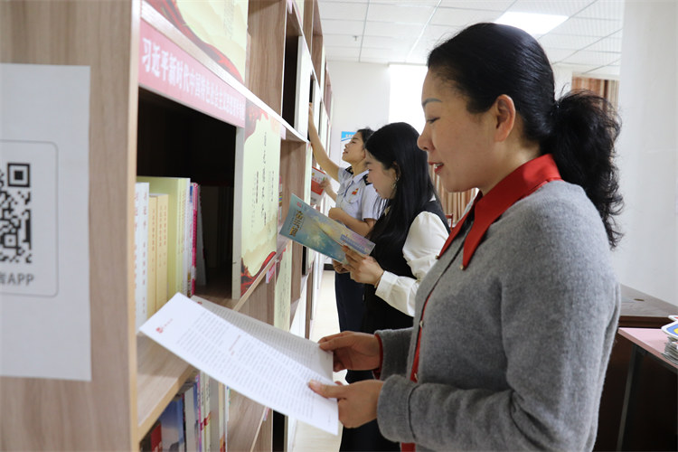 税务干部和社区工作人员在共享图书馆一起阅读税务读本。达州市税务局供图