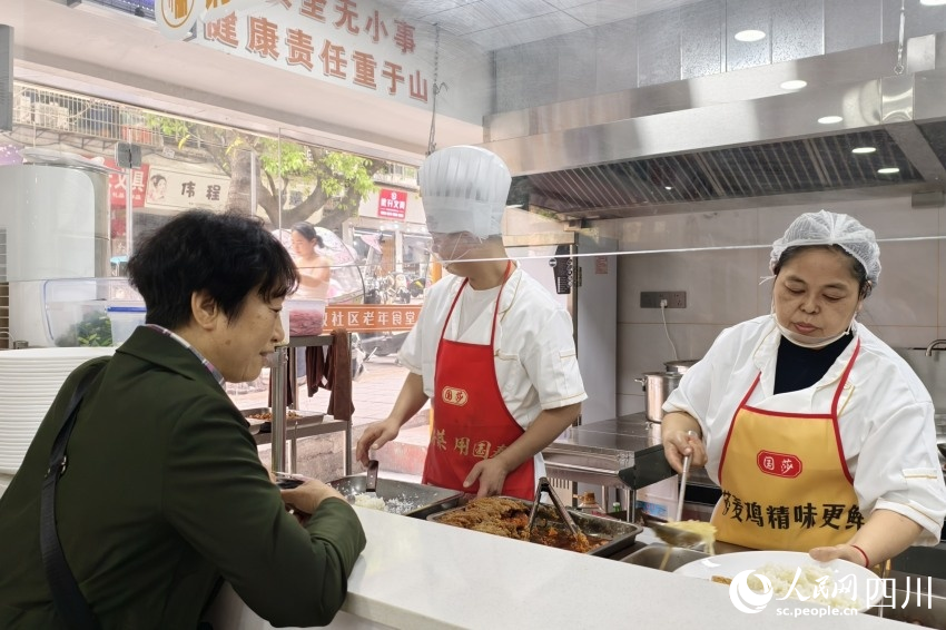 老年食堂取餐口前，厨师正在按需为老人打饭。人民网 赵祖乐摄