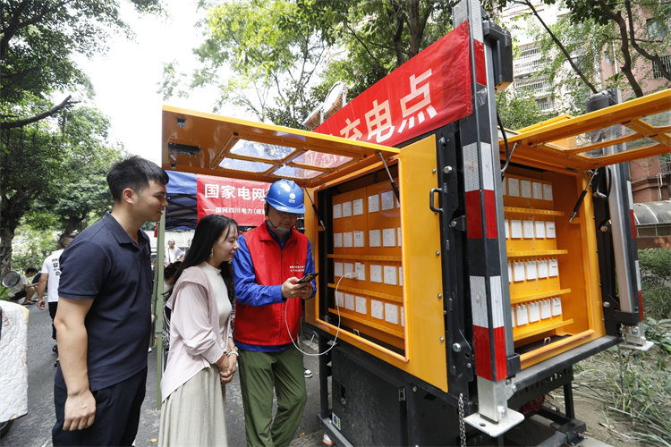 7月4日，在成华区银锣湾小区，国网成都供电公司成华供电中心设置应急充电点，共产党员服务队队员为居民提供现场充电服务。陈红梅摄