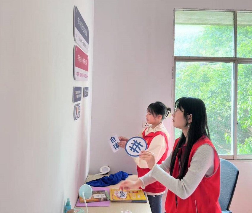 志愿者在帮扶对象卧室张贴“励志标语”。广安市烟草专卖局供图