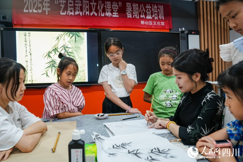 四川大学锦江学院“90后”副教授高子然在眉山市彭山区文化馆为孩子们讲解中国画知识。人民网 赵祖乐摄