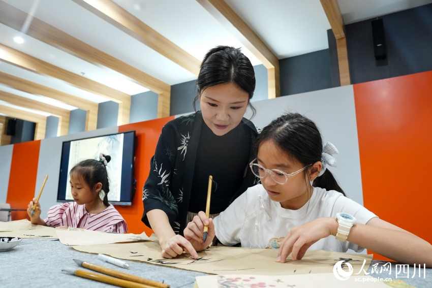 四川大学锦江学院“90后”副教授高子然在眉山市彭山区文化馆指导孩子们画中国画。人民网 赵祖乐摄