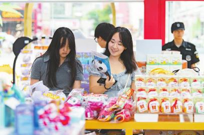 7月14日，游客在官方特许商品零售店红星路店挑选世运会周边商品。