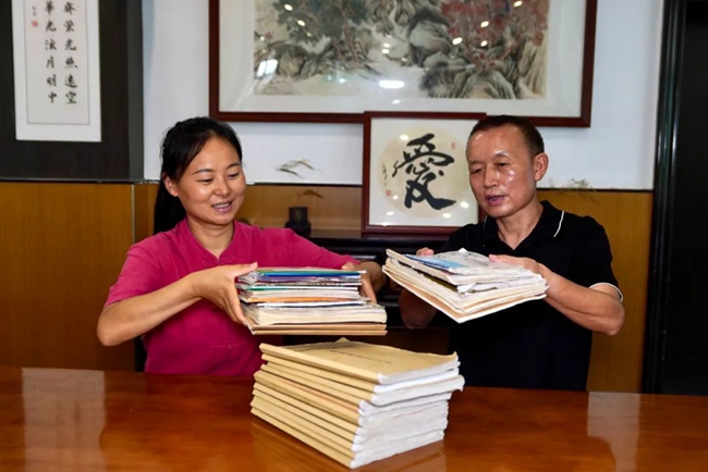 2025年7月30日，王成富和店长李小娟整理8年来免费人员吃饭登记册。刘婷供图