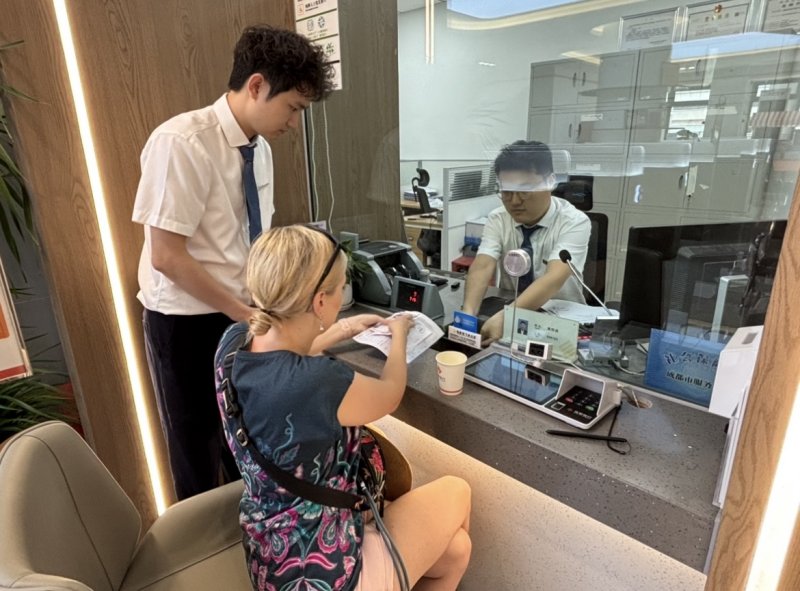 为从波兰来成都旅游的游客将100美元兑换成人民币。唐聪摄