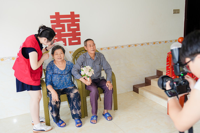 志願者為金婚夫婦拍攝合照現場。余文攝