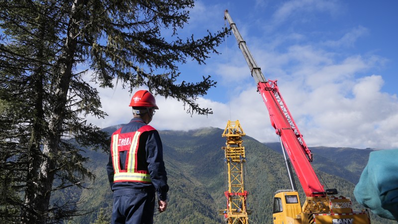 10月1日，在海拔3200余米的阿壩—成都東1000千伏特高壓交流輸變電工程1標段1R013號塔位，現場負責人正在督導作業人員開展雙搖臂抱杆組塔工作。尤琅攝