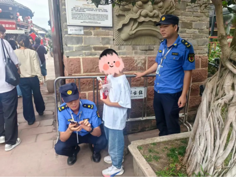 在洛帶古鎮景區，執法人員幫走失兒童聯系父母。成都市城市管理委員會供圖