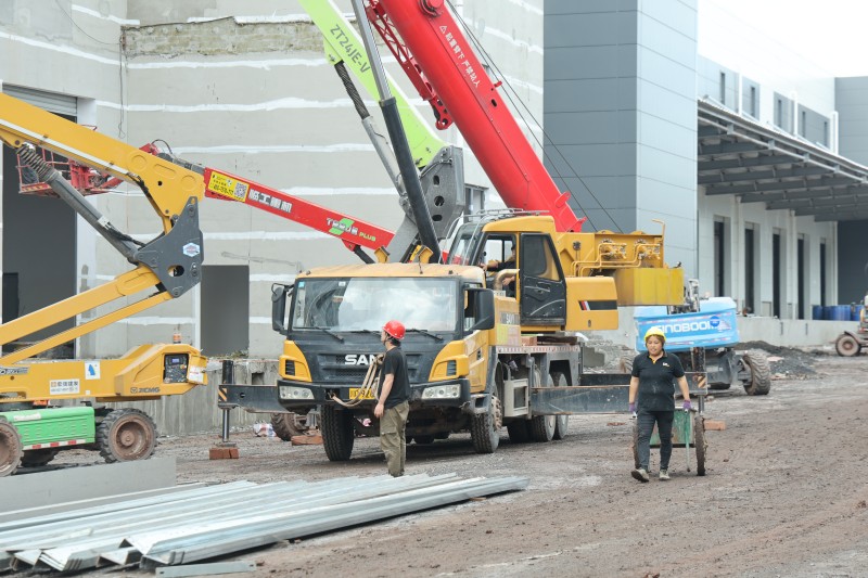 项目现场大型机械与工人配合开展作业。翠屏区融媒体中心供图