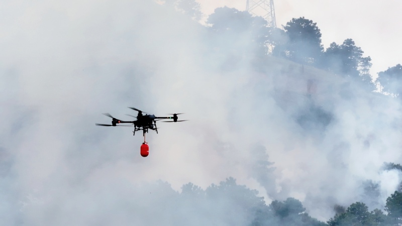 无人机挂载灭火弹进入火场压制火势。李威摄