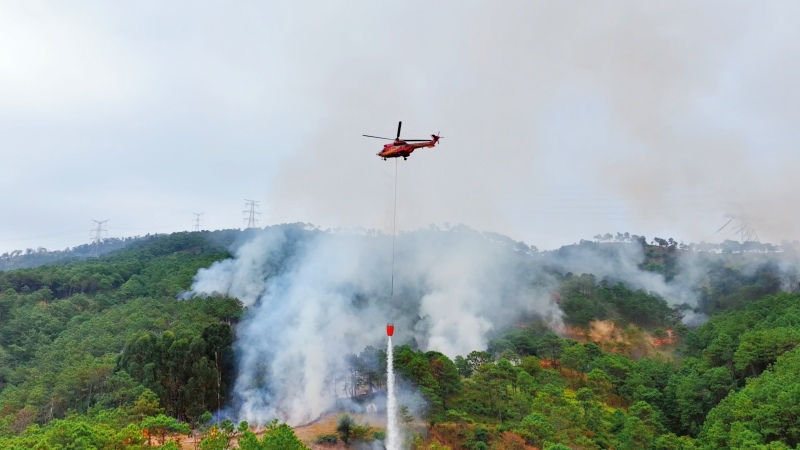 直升机挂载吊桶精准喷洒关键火点。李威摄