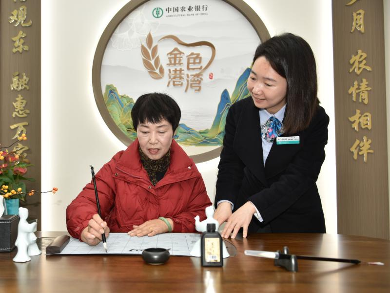 农行员工（右）陪伴老年客户练书法。农行四川省分行供图