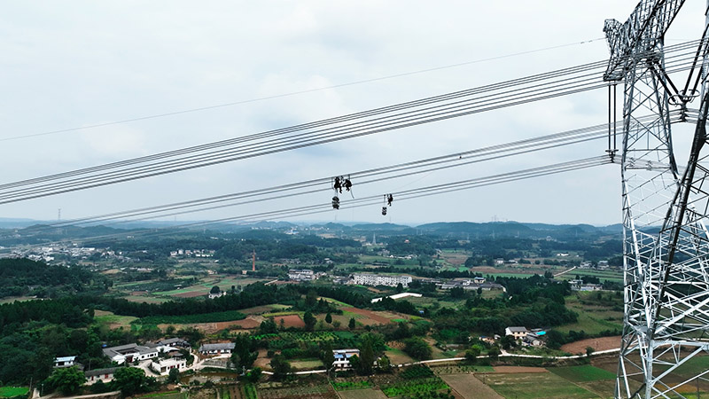 12月25日，在德阳市中江县，阿坝—成都东1000千伏特高压交流输电工程15标导线展放作业现场，国网四川电力工人正在安装间隔棒。国网四川建设公司供图