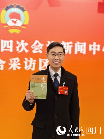 四川省政協委員、眉山市政協主席黃劍東在採訪間隙薦書。人民網記者 郭瑩攝