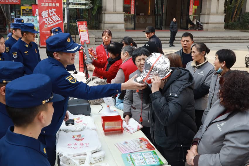 广元支队帮助社区群众正确佩戴防火防烟面罩。广元市消防救援支队供图