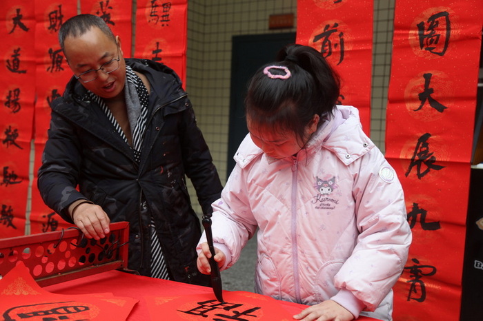 书法家手把手教导小学生写“福”字。马发海摄