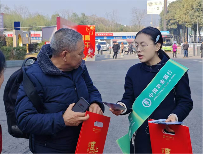 农行达州支行工作人员在车站向返乡农民工送福袋。农行四川省分行供图