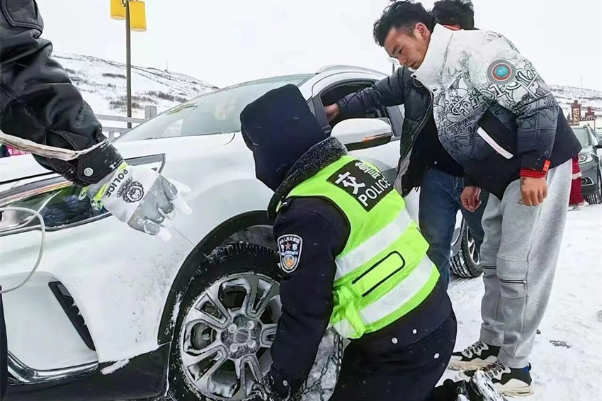雪地中，民警正在幫自駕游客裝防滑鏈。四川省公安廳供圖