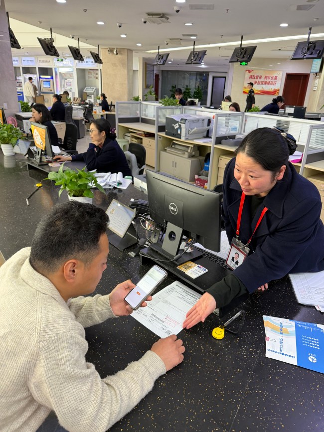 窗口工作人员向办事人说明综合告知单上的二维码功能。成都市金牛区政务服务管理和行政审批局供图