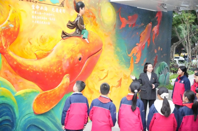自贡市汇东实验学校的美术老师刘颖正在给学生们讲墙绘作品《大鱼海棠》的色彩搭配。自贡高新区住房和城市更新局供图