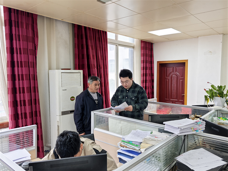 王胤丰（右）正在向群众宣讲解读社保相关政策。乔剑摄