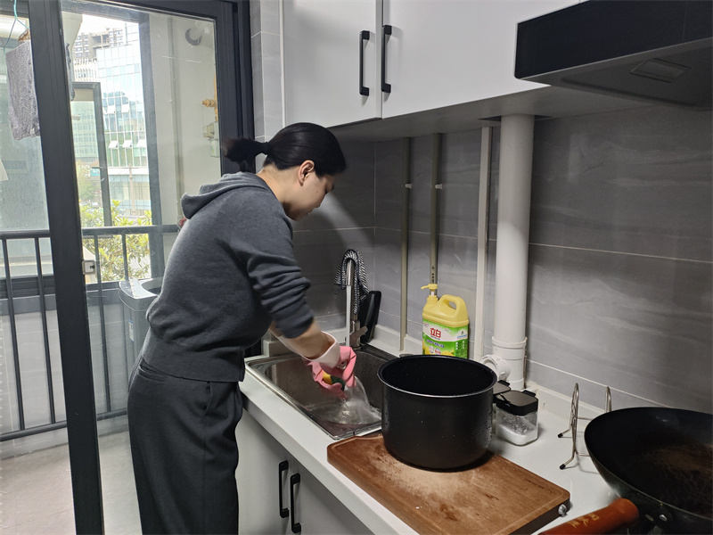 新市民張先生正在做飯。黃成薇供圖