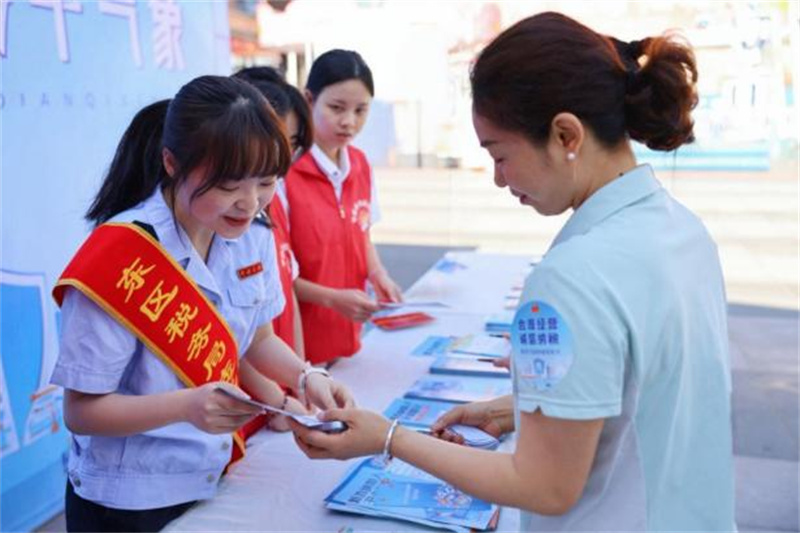 税务干部和志愿者向商家宣传诚信经营相关内容。攀枝花市税务局供图