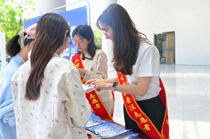 活动现场，大学生税收普法志愿者为过往师生讲解税费政策。成都市税务局供图