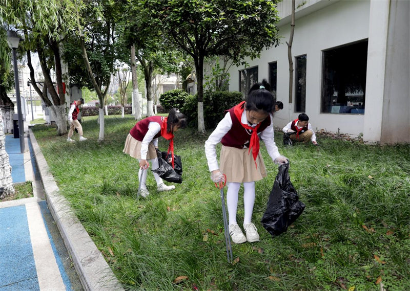 4月22日，广安市广安区富源小学学生在广福街道西溪社区清理公共绿地垃圾。