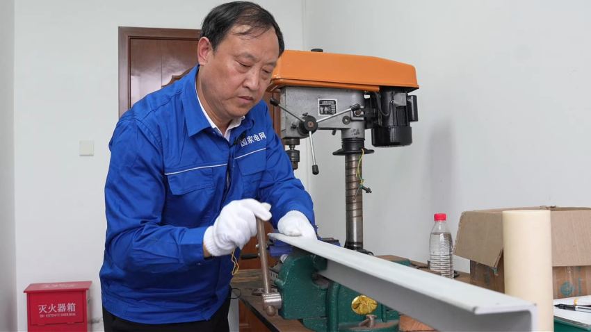 国网内江供电公司金鹅供电所党支部书记陈明煜，在操作间里尝试加工制作创新产品样品。侯涛摄