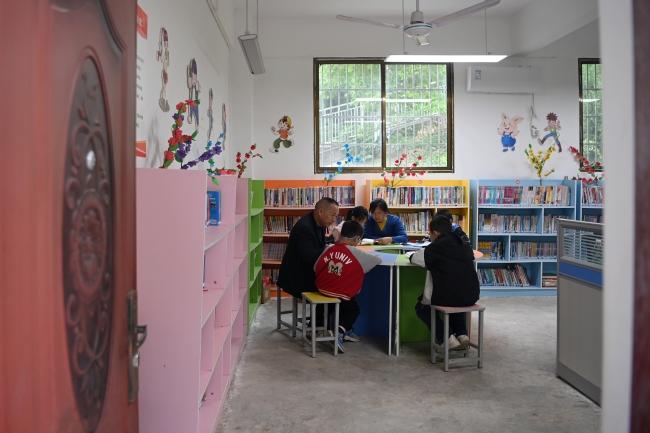 周建波和陈蓬珍夫妇在图书室陪孩子们看书。周亮供图