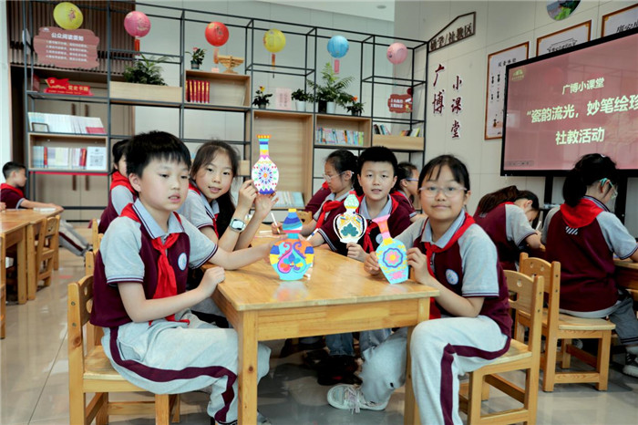 5月18日，四川省广安市广安区富源小学学生在广安市博物馆参加“瓷韵流光 妙笔绘珍”社教活动，展示自己彩绘的故宫瓷瓶饰物。