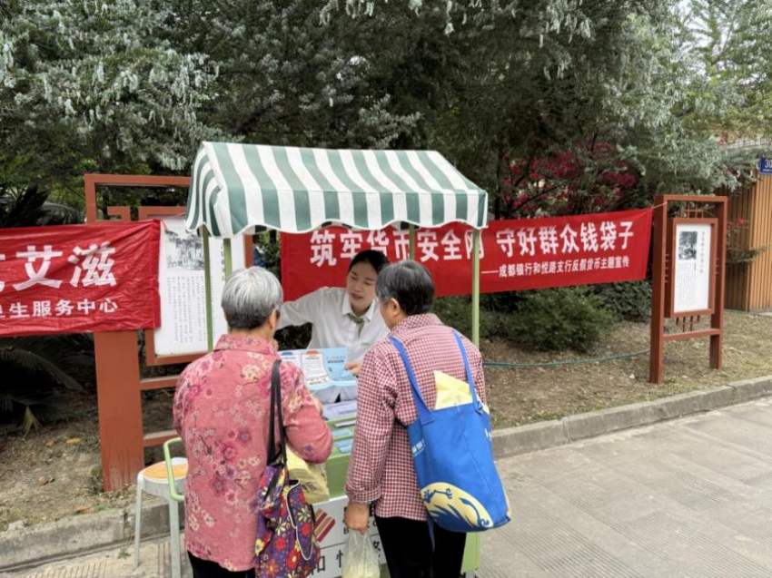 成都银行和悦路支行工作人员拿着人民币宣传资料，向小区居民们宣传人民币防伪知识。主办方供图