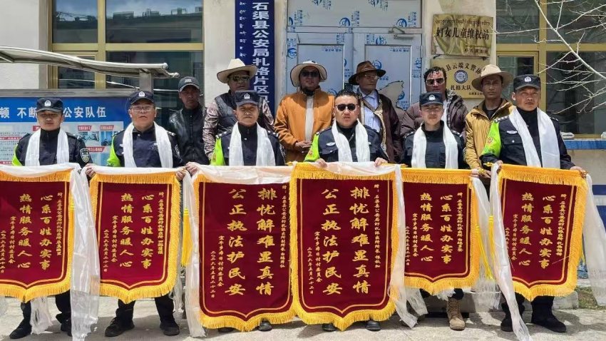 受害群眾及村委會代表將6面錦旗送到民輔警手中。石渠公安供圖
