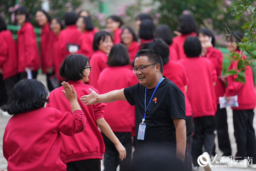 6月9日,进入考场前,老师与学生与每一位即将入场的学生击掌、碰拳,为他们加油助威。人民网记者 李发兴摄