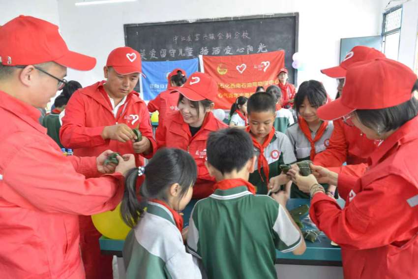 “心气”志愿者与中江县福兴镇会棚中心小学学生一起包粽子。杨凌博摄
