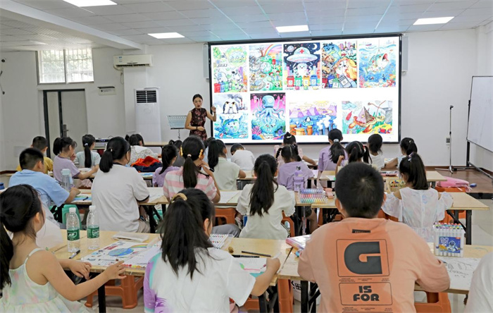 7月7日，在广安市广安区文化馆公益暑托班，志愿者在向社区学生进行美术创作辅导。