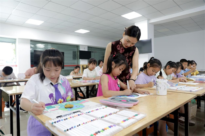 7月7日，在广安市广安区文化馆公益暑托班，志愿者在指导学生进行绘画创作。