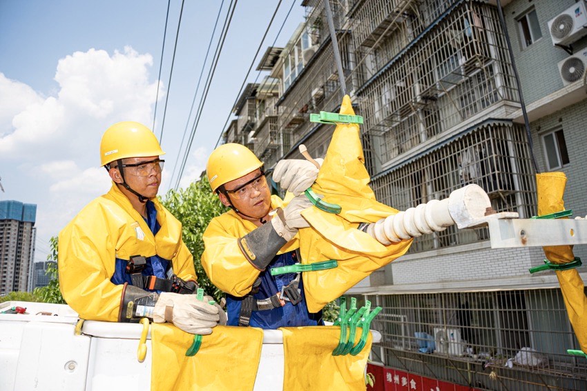 7月6日，在绵阳市涪城区，国网绵阳供电公司工作人员正在开展带电作业。田海摄