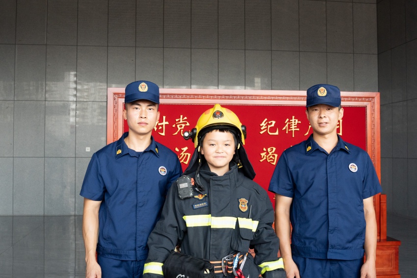 小朋友穿上全套灭火战斗服，与消防员合影留念，沉浸式体验消防员的装备，感受消防职业的责任与担当。四川省消防救援总队供图