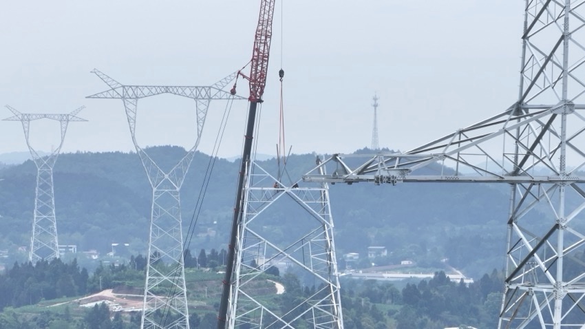 在四川省绵阳市，阿坝—成都东1000千伏特高压交流工程作业人员正在开展吊车组塔。国网四川建设公司供图