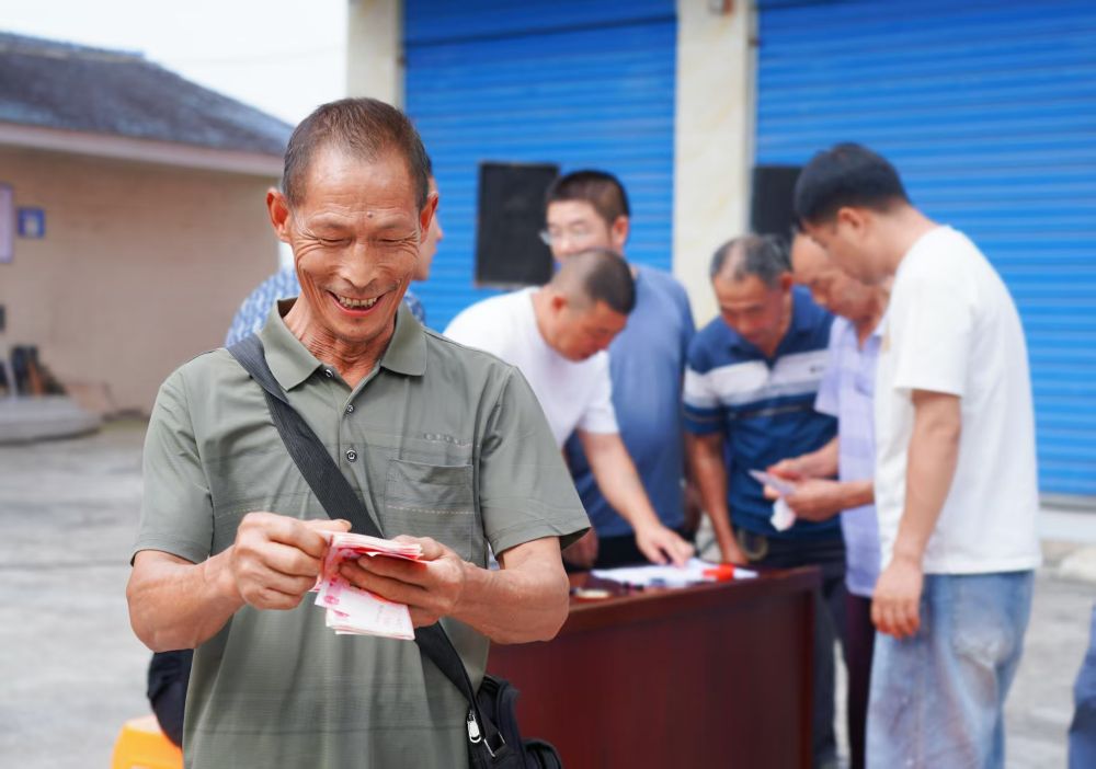 在巴中市恩阳区玉山镇“幸福晒场”活动中，现场兑现高标准农田建设项目拖欠群众劳务费。图为，村民现场领到劳务费后喜笑颜开。李红供图